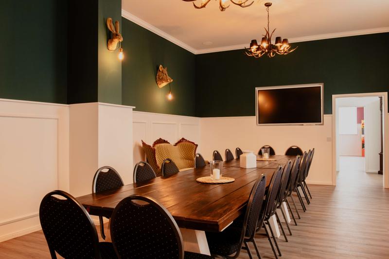 Veranstaltungsraum mit langem Tisch und großem Fernseher